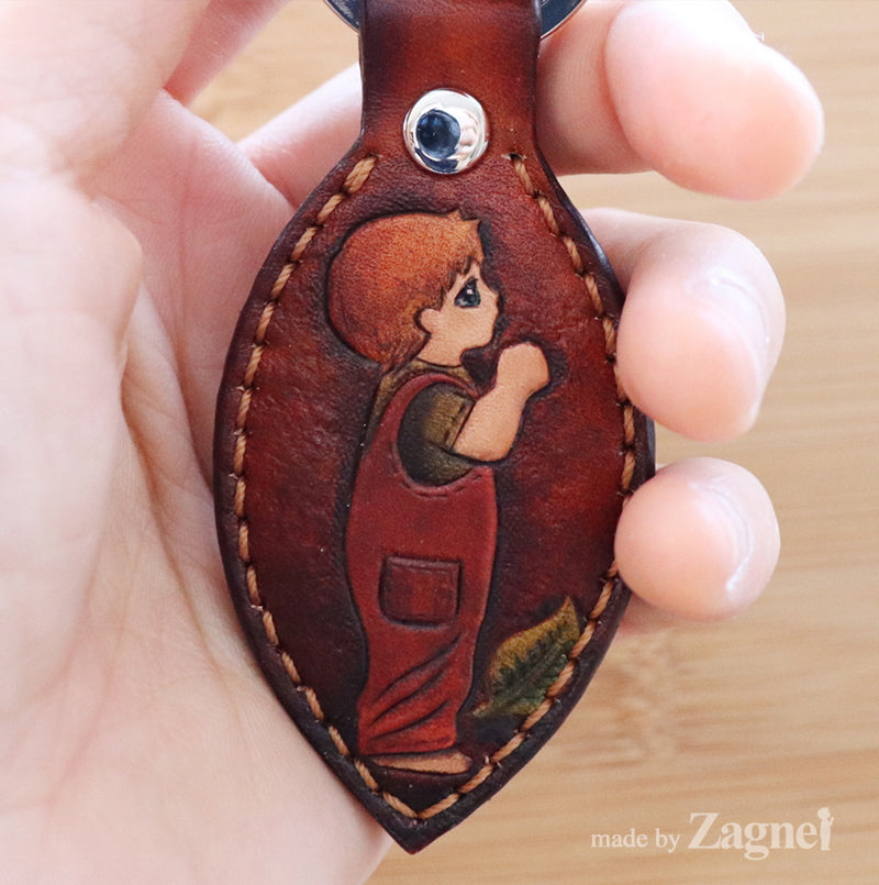 A leather keychain with a carved boy